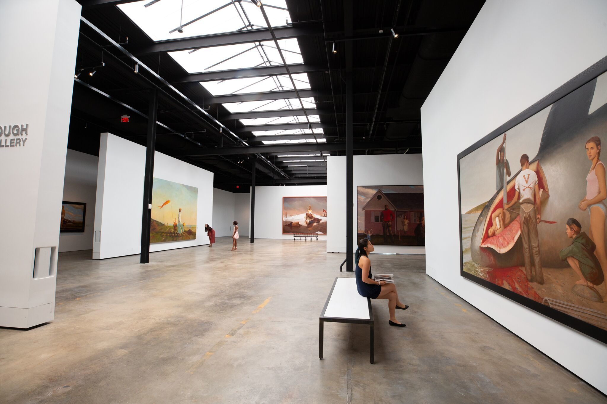 A visitor sitting in front of the many wall-sized paintings by Columbus native Bo Bartlett.