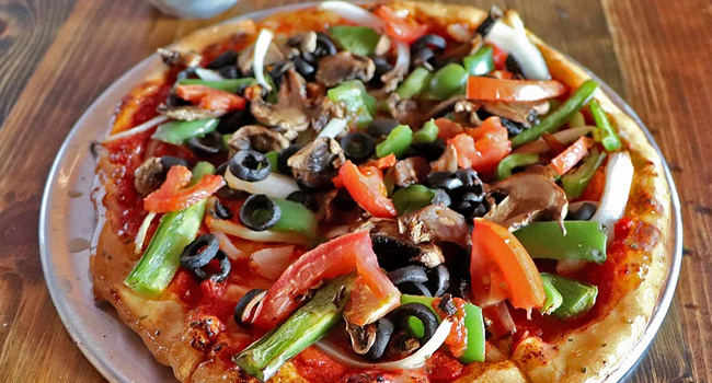 pizza with a ton of veggies on top including peppers, mushrooms, olives, and more
