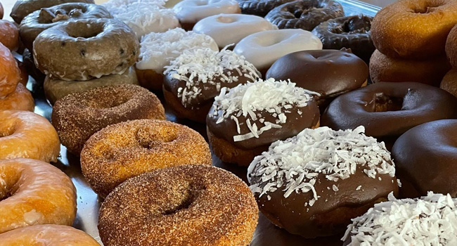 various rows of donuts including chocolate and coconut topped donuts