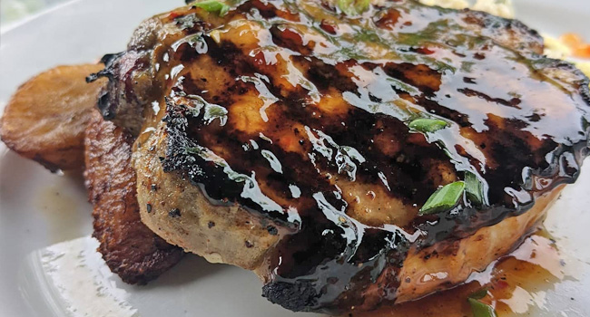 glazed pork chop and roasted potatoes on restaurant table